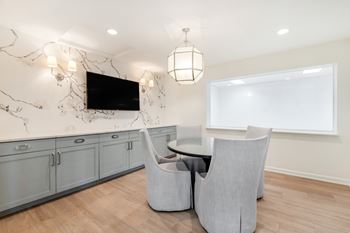 A modern living room with a television, grey armchairs, and a marble backsplash
